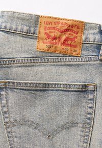 Džíny Levi's 531 s jemnou modrou denimovou strukturou, s hnědou koženou nášivkou označenou "LEVI STRAUSS & CO" na zadním pásu.
