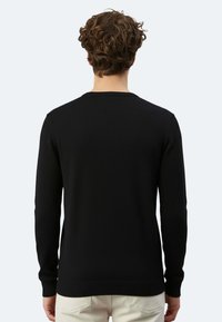 Schwarzer Strickpullover mit langen Ärmeln, Rundhalsausschnitt und gerippten Bündchen. Glatte Textur ohne auffällige Muster oder Akzente.