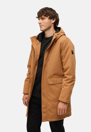Tan hætteparka med lynlås foran, sidelommer og sort indvendig foring, lavet af et glat og slidstærkt stof.