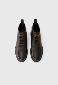 Botas de tobillo de cuero marrón con acabado liso, que cuentan con un diseño de cordones, una lengüeta en la parte posterior y una suela de goma.
