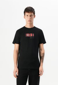 Zwarte katoenen T-shirt met een rood en wit grafisch ontwerp op de voorkant. Korte mouwen en een klassieke ronde hals.