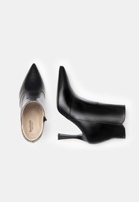 Botas de tobillo de cuero negro con tacones altos y puntiagudos, textura suave, cierre lateral y tacones delgados tipo stiletto.