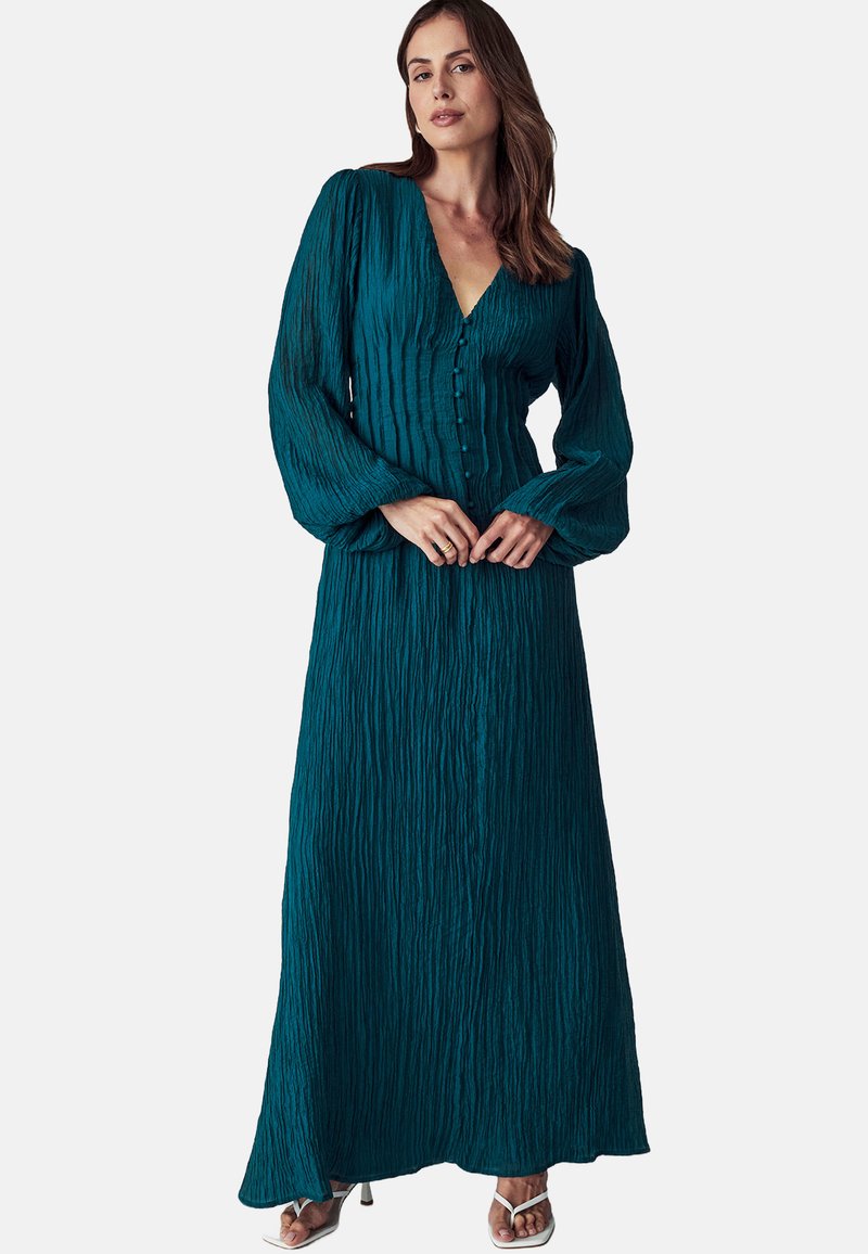 Tannend grüne Maxikleid aus strukturiertem Stoff, mit langen, luftigen Ärmeln, einem V-Ausschnitt und Knöpfen an der Vorderseite. Der Rock fällt frei bis zu den Knöcheln.