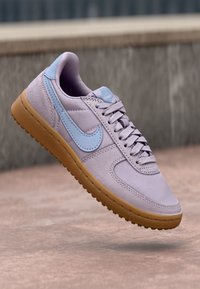 Baskets lilas avec une tige en daim, accents bleus et une semelle en caoutchouc transparent. Présente un design classique à lacets et un bout arrondi.