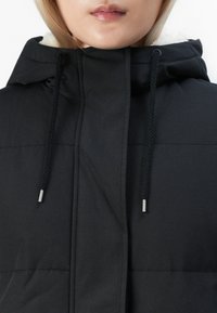 Doudoune noire avec capuche, dotée d'une doublure blanche douce et de cordons noirs épais avec embouts argentés. Texture lisse et design matelassé.