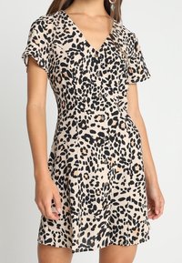 Abito in stampa leopardata realizzato in tessuto leggero, con maniche corte, scollatura a V e bottoni lungo la parte anteriore, con orlo svasato.