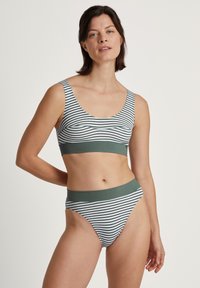 Vartaloon sopiva raitabikini-setti, jossa on valkoista ja vihreää. Settiin kuuluu avonainen bralette, jossa on erottuva vyötärönauha, sekä korkeatehoiset, kapenevat bikinit.