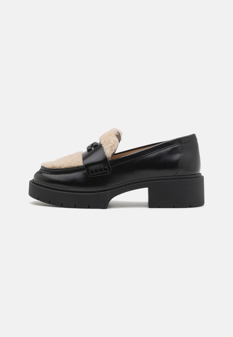 Black leather loafers with a shearling accent, featuring a thick, textured platform sole and a decorative strap across the front.
