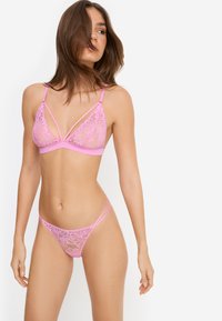 Ροζ δαντελένιο μπραλέτα με κεντήματα με λουλούδια, λεπτομέρειες με λουράκια και μαλακή υποστήριξη κάτω μέρος. Το τάνγκο που ταιριάζει διαθέτει παρόμοιο σχέδιο δαντέλας και ρυθμιζόμενα λουράκια.