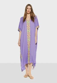 Lila kaftan med V-ringning, prydd med färgglad mönstrad kant längs fram och ärmar; lättviktig tyg, lös passform, knälång.
