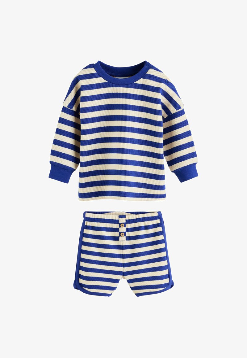 Tenue pour tout-petit avec haut à manches longues et short, présentant des rayures horizontales bleues et crème et des poignets côtelés bleus.
