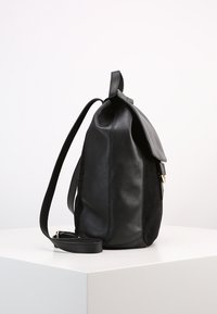 Černá kožená taška s hladkým povrchem, s klopou, nastavitelným popruhem a jemnými švy. Zaoblený tvar s měkkou texturou.