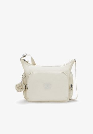 Beige crossbody bag with front pocket, adjustable strap, side zipper pockets, and a small plush monkey keychain attached.