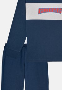 Navy blue loungewear set with a long-sleeve top featuring a white and red “CONNECTED” graphic, and matching elastic waistband pants.