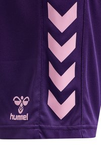 Lila sportshorts med ett rosa zigzag-mönster på sidan och en liten vit logotyp med texten "hummel" längst ned.