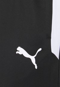 Black athletic shorts made of smooth fabric, featuring a white Puma logo and textured white side panels for contrast.