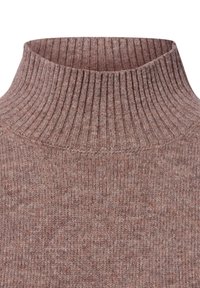 Brown ribbed turtleneck sweater, textured knit with a high collar. Features a soft, warm material. Close-up of neckline and fabric detail.