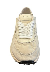 Sneaker beige con punta in suede, parte superiore in tessuto trapuntato, lacci bianchi e suola in gomma nera con motivi circolari antiscivolo.
