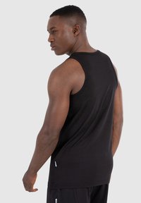 Schwarzes ärmelloses Tanktop aus Baumwolle. Verfügt über einen runden Ausschnitt, einen lockeren Schnitt und seitliche Akzent-Tags. Glatte Textur, minimalistisches Design.