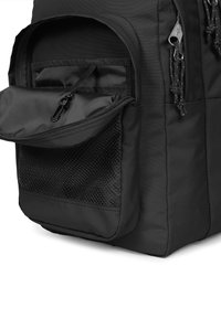 Svart ryggsäck med en dragkedja framficka och en meshliknande sidoficka. Hållbart tyg med slät yta och justerbara axelremmar.