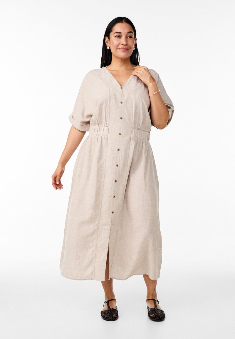 Beige linne maxi klänning med V-hals, korta rullade ärmar, knäppning fram och elastisk midja. Har en medellång slits och knappar.
