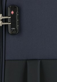 Valigia di tessuto blu navy con superficie texture, dotata di una serratura nera approvata TSA e di hardware per cerniera argentata.