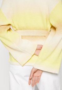 Jersey de punto con un patrón degradado que va de amarillo claro a crema, con cintura ce�ñida, mangas anchas y puños y dobladillo acanalados.