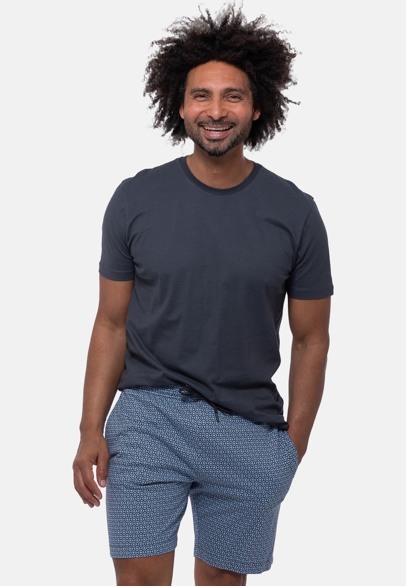 Navy-blaues T-Shirt mit kurzen Ärmeln, kombiniert mit hellblauen gemusterten Shorts mit geometrischem Design. Der Stoff wirkt weich und atmungsaktiv.