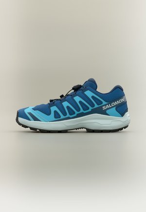Blauer Salomon Laufschuh mit hellblauen Akzenten, schwarzen Zuglaschen-Schnürsenkeln, weißer Sohle und schwarzem Profil, von der Seite auf neutralem Hintergrund dargestellt.