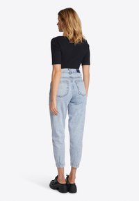 Top corto a maniche corte nero a coste abbinato a jeans in denim azzurro chiaro a vita alta. I jeans presentano una vestibilità affusolata e due tasche sul retro. Scarpe con plateau nere.