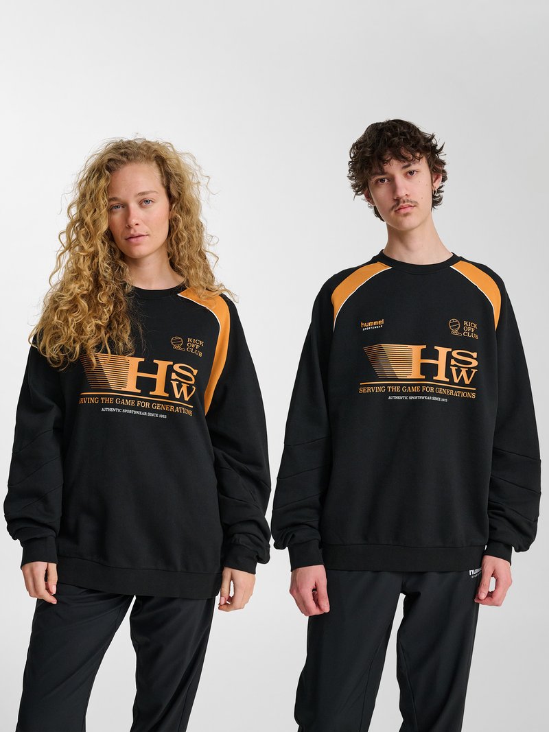 Zwei junge Erwachsene tragen passende schwarz-orangene Sport-Sweatshirts mit den Schriftzügen "HSW" und "Kick Off Club" und stehen vor einem einfarbigen Hintergrund.