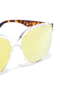 Clear frame sunglasses with yellow lenses, oversized cat-eye shape, and tortoiseshell patterned temple arms. Brand name "BE VUCHO" visible.
