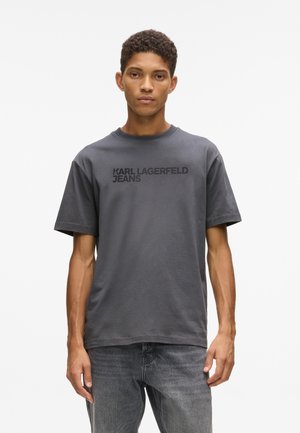 Šedé bavlnené tričko s krátkymi rukávmi, s čiernym logom "KARL LAGERFELD JEANS" napísaným na hrudi. Priame zakončenie a okrúhly výstrih.