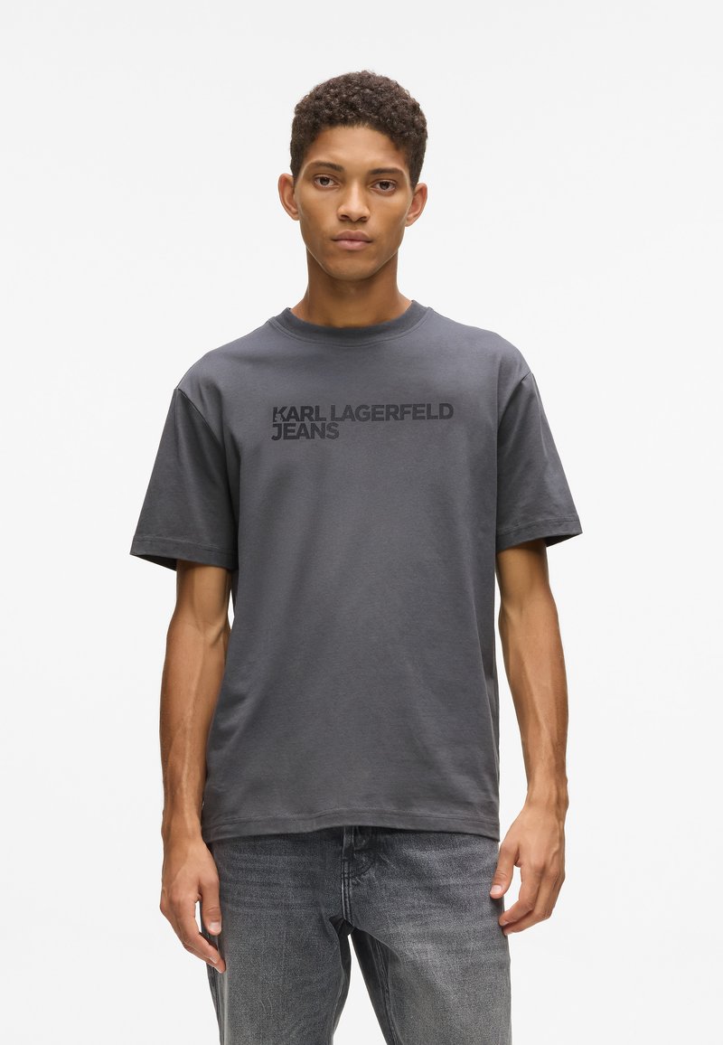 Szara bawełniana koszulka z krótkim rękawem, z logo "KARL LAGERFELD JEANS" w czerni na piersi. Prosta, ściągająca u dołu i okrągły dekolt.