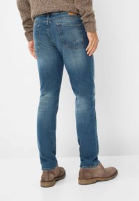 Slim-fit blauwe jeans gemaakt van denim, met een klassieke vijf-pocketontwerp, vervaagde textuur, en gecombineerd met bruine suède enkellaarsjes.