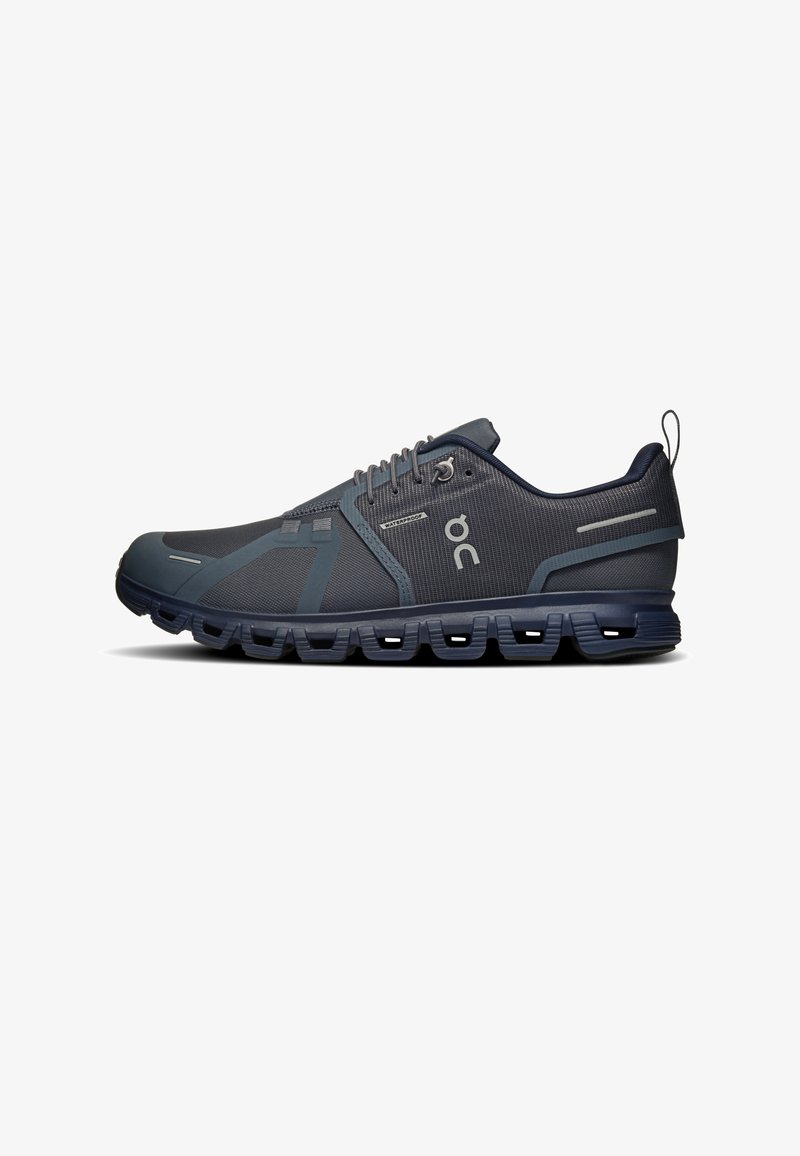 Chaussure de course athlétique bleu foncé avec empeigne en mesh, semelle segmentée distinctive, fermeture à lacets, petite étiquette imperméable et logo On Running sur le côté.