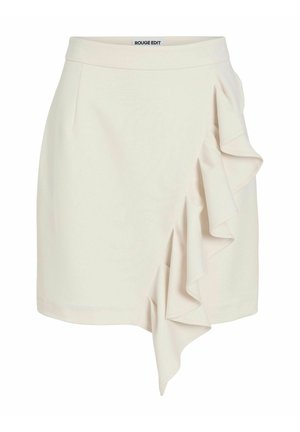 Mini-jupe de couleur crème avec un détail de volant asymétrique sur le côté droit et une ceinture ajustée portant l’étiquette « ROUGE EDIT ».