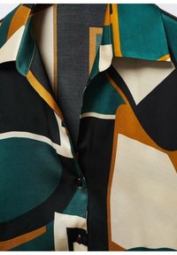 Blouse en satin avec un motif abstrait audacieux en teal, noir, crème et orange. Comprend un col classique et des détails de boutons.