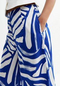 Pantaloni blu e bianchi con motivo, caratterizzati da una vestibilità ampia, tessuto morbido, con audaci design a pennellate e tasche laterali.