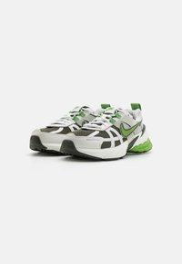 Zapatillas deportivas con parte superior de malla en blanco y gris, acentos en verde y una suela gruesa verde. Cuentan con cordones y un logo prominente.