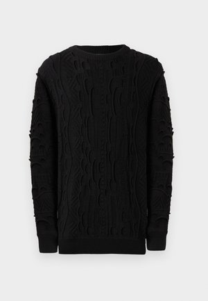 Zwarte gebreide trui met tekstuurpatronen, voorzien van een geribbelde ronde hals en lange mouwen. Het ontwerp bevat verhoogde geometrische motieven door het geheel.