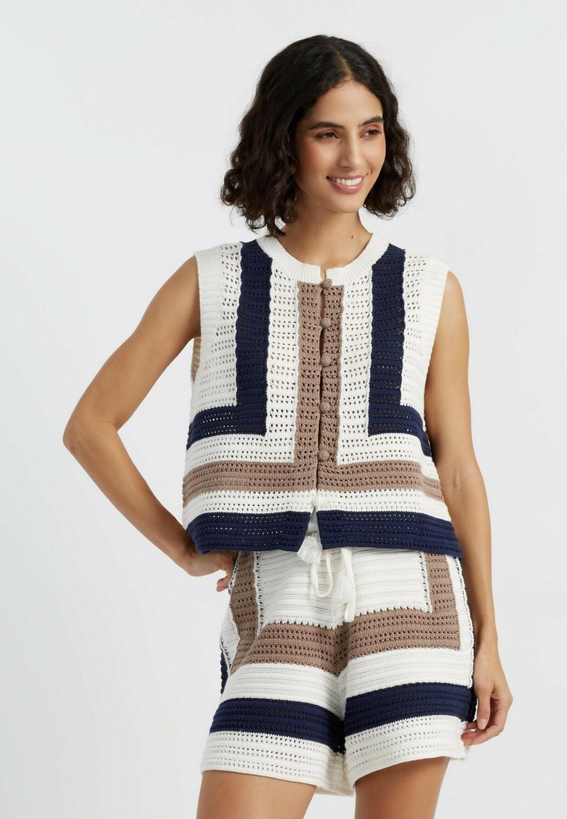Gehaakte brei-vest in wit, marineblauw en bruine strepen; korte mouwen; ronde halslijn; decoratieve knoopsluiting aan de voorkant; ontspannen pasvorm.