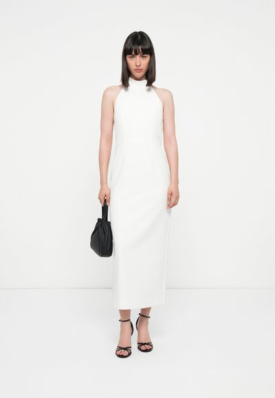 Witte halterneck jurk met een slanke pasvorm, rechte rok en geen zichtbare versieringen, gecombineerd met zwarte accessoires.