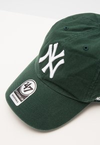 Casquette de baseball en coton vert avec un logo NY brodé en blanc à l'avant, dotée d'un bord courbé et d'une sangle réglable pour la taille.