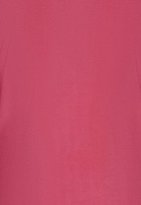 Fleece stof in felroze, zachte textuur, uniforme kleur, geen patronen of accenten zichtbaar, glad oppervlak met een lichte glans.