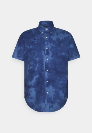 Chemise à manches courtes avec col boutonné et motif tie and dye bleu sur un fond uni.