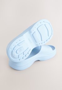 Chaussures bleu clair à enfiler avec une semelle en caoutchouc texturée, dotées d'une tige lisse et d'une conception à bout ouvert. Idéales pour une tenue décontractée.