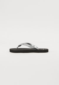 Sølvrutete flip-flopsandal med en teksturert svart gummisåle. Har en blank stropp og preget logo detaljering på stroppen.