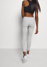 Leggings grises con un acabado texturizado, combinados con un top corto negro. El conjunto se complementa con zapatillas deportivas blancas.