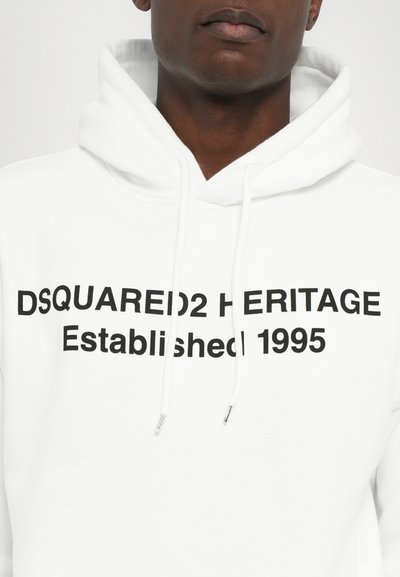 White hoodie made of cotton, featuring black text: "DSQUARED2 HERITAGE Established 1995." Includes drawstrings and ribbed cuffs.